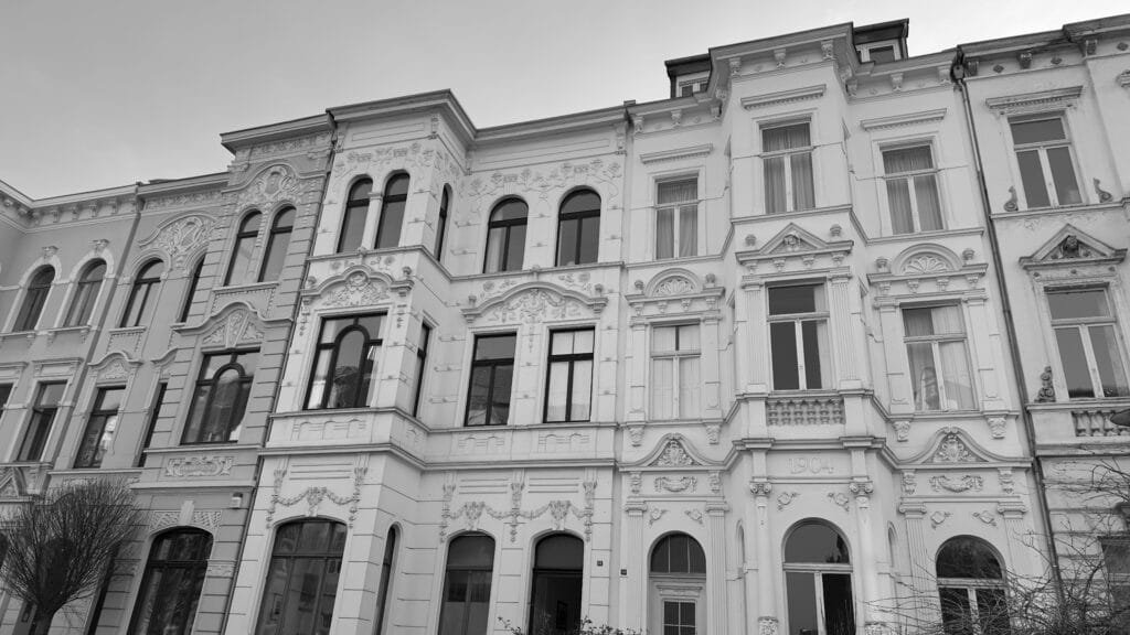 Façades en noir et blanc de maisons bourgeoises Art Nouveau aux ornements sculptés, fenêtres cintrées et millésime visible.