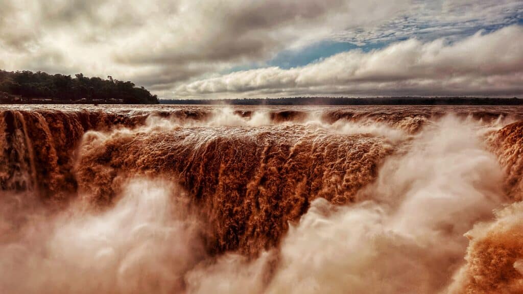Cascades imposantes d'eau blanche et écume rousse tombant en torrent sous ciel nuageux